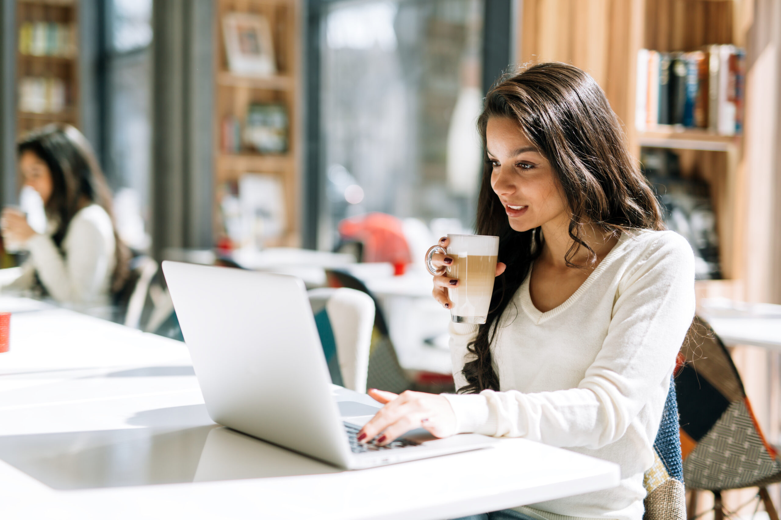 Beautiful brunette enjoying coffee and using laptop